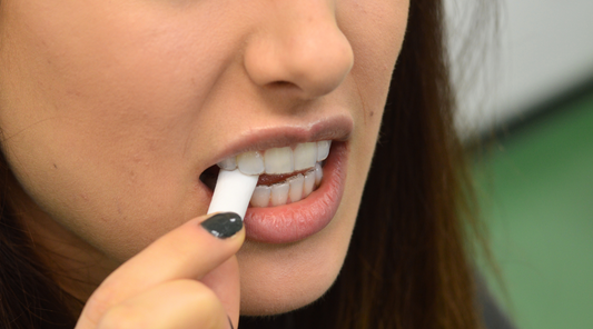 Close-up photo of woman with white chewy between teeth