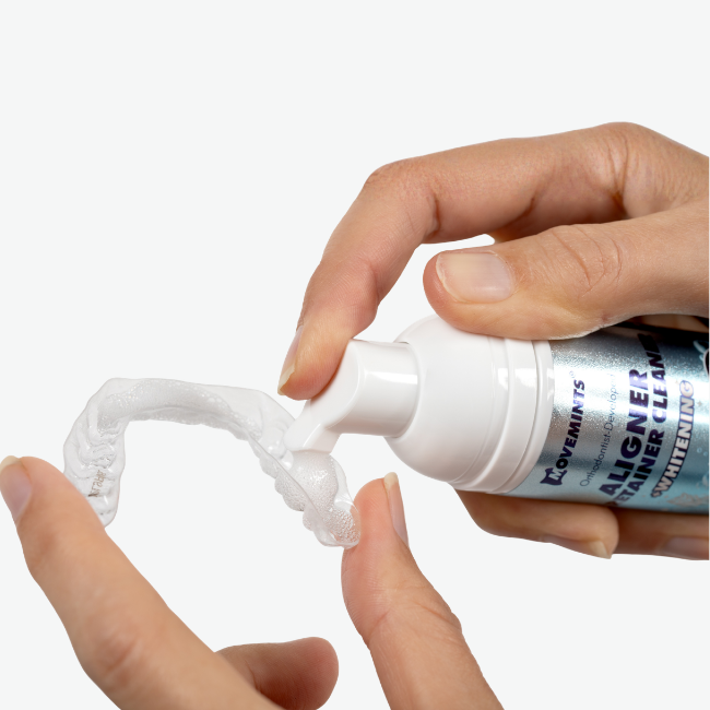 Hand applying Movemints Aligner & Retainer Cleaning Foam + Whitening into an aligner