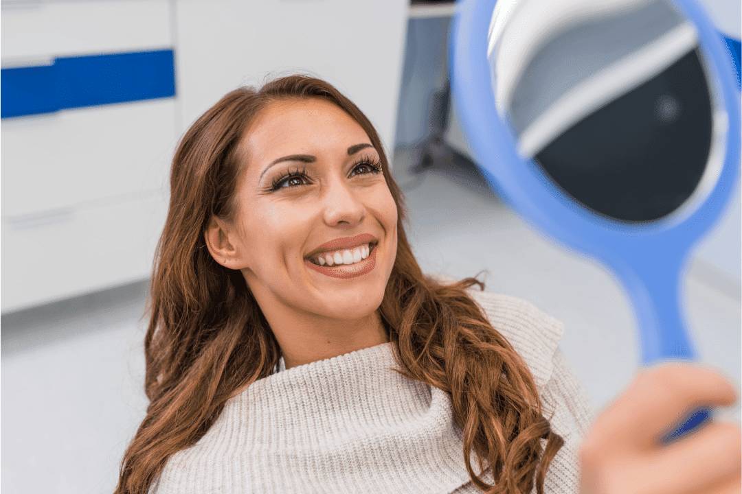 woman admiring smile in handheld mirror