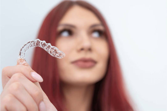 young woman holding clear retainer red hair